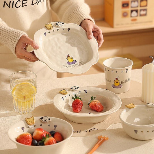Ceramic dishes with cartoon designs on a table with fruit and a glass of juice.