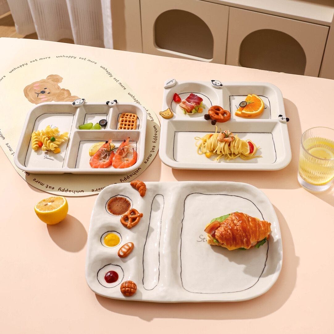 Children's divided plates with food on a light pink surface