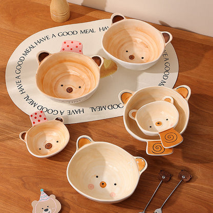 Set of bear-shaped ceramic bowls on a wooden surface with a decorative mat.