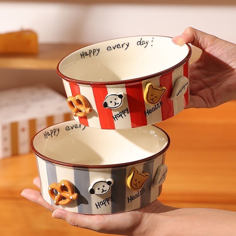 Two ceramic bowls with decorative elements and text, held by a person.