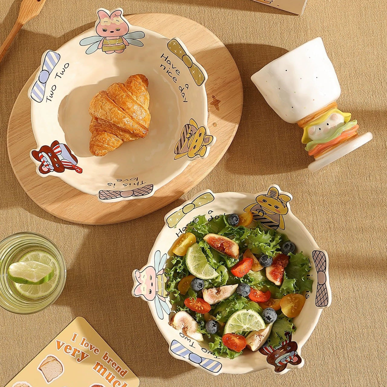 Children's table setting with cartoon-themed plates, cups, and cutlery on a brown tablecloth.