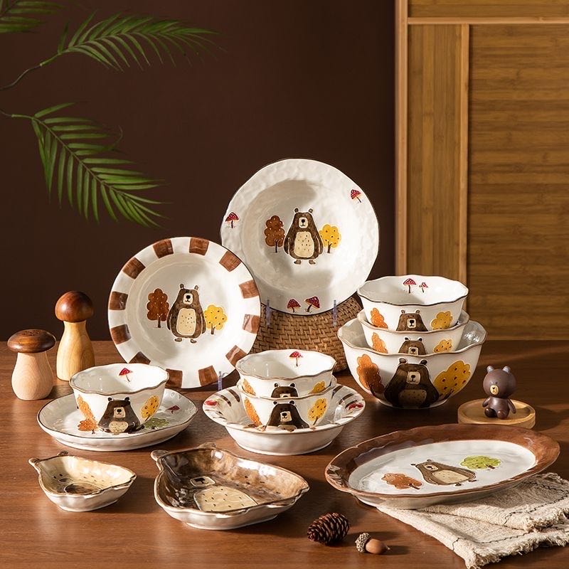 Set of ceramic dishes with animal illustrations on a wooden table.