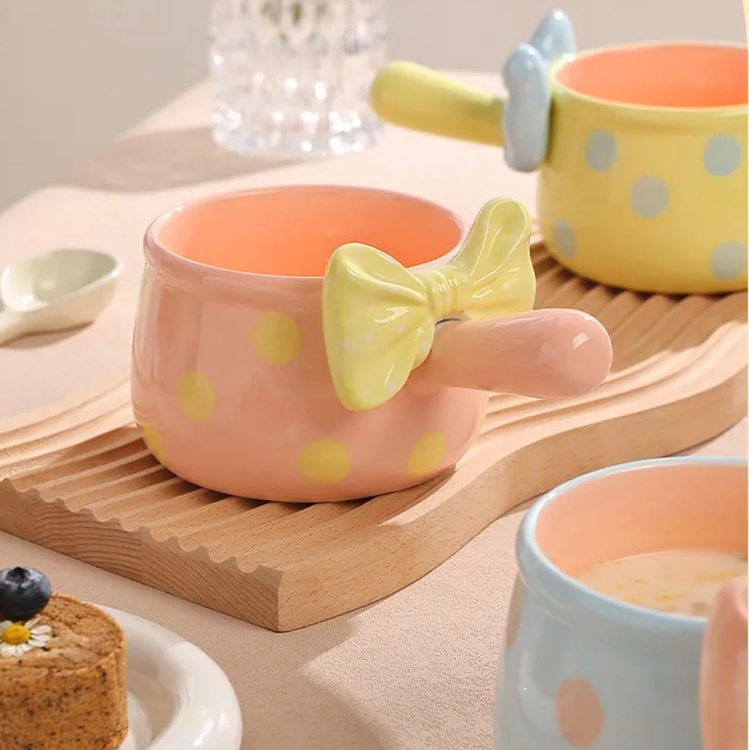 Cute ceramic cups with polka dots and a bow on a wooden tray.