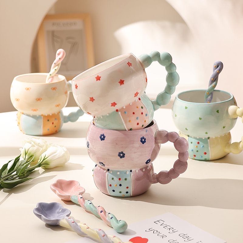 Set of colorful ceramic mugs and spoons on a light surface with a blurred background