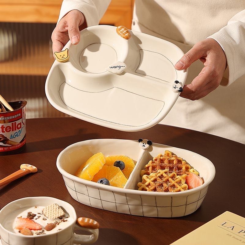 Person holding a cat-shaped dish with food on a wooden table
