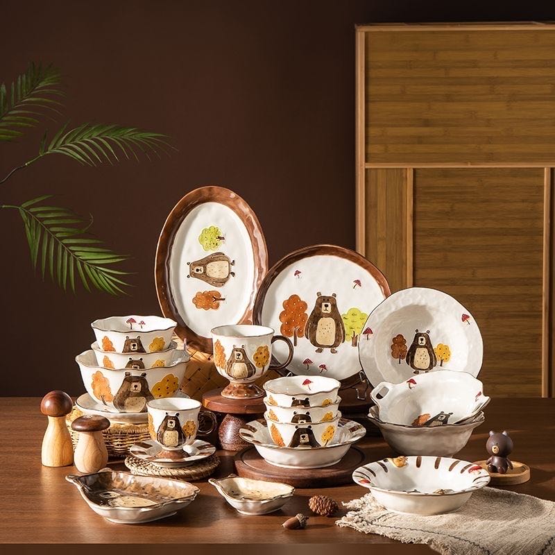 Ceramic tableware set with animal illustrations on a wooden surface.