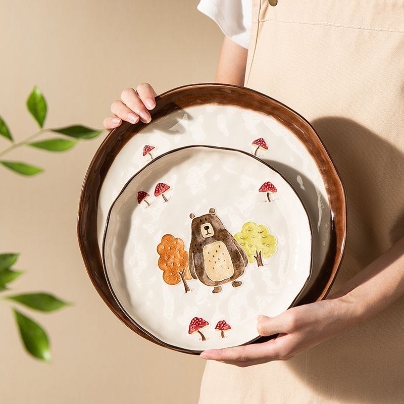 Person holding a ceramic plate with a bear design on a beige background