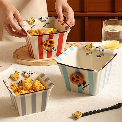 Ceramic snack bowls with striped patterns and cartoon characters on a table.