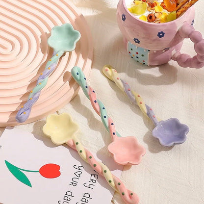 Set of colorful ceramic spoons on a textured surface with a mug in the background.