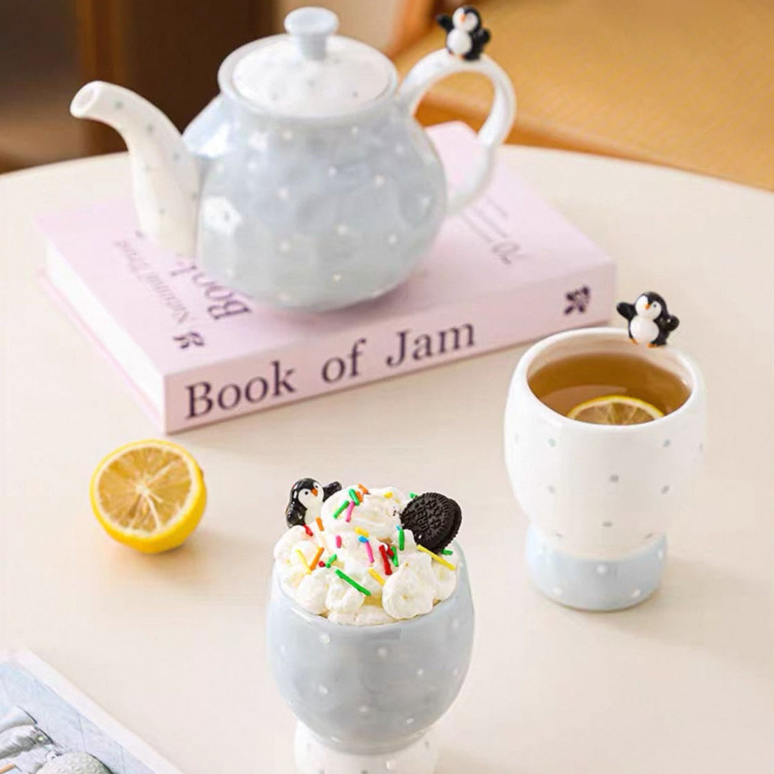 Ceramic teapot and cups on a table with a book in the background