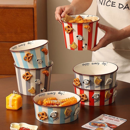 Person holding a striped popcorn bucket with cartoon characters, surrounded by similar buckets on a table.
