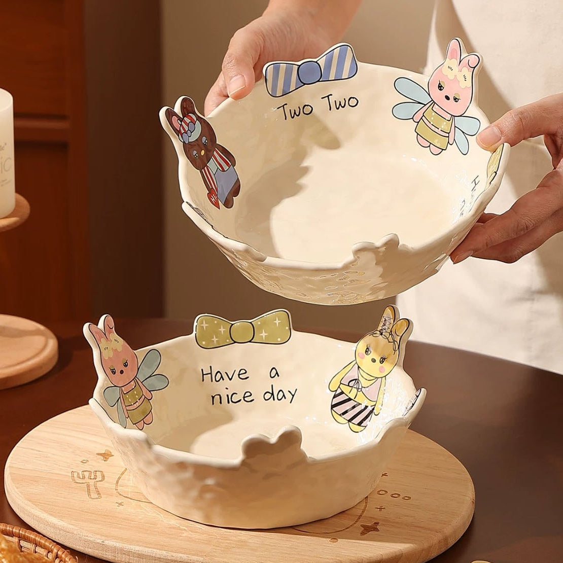 Person holding a decorative bowl with cartoon characters on a wooden table.