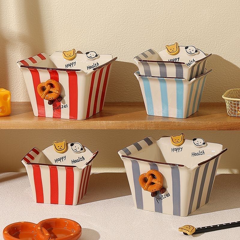 Decorative bowls with striped patterns and cartoon characters on a wooden shelf.