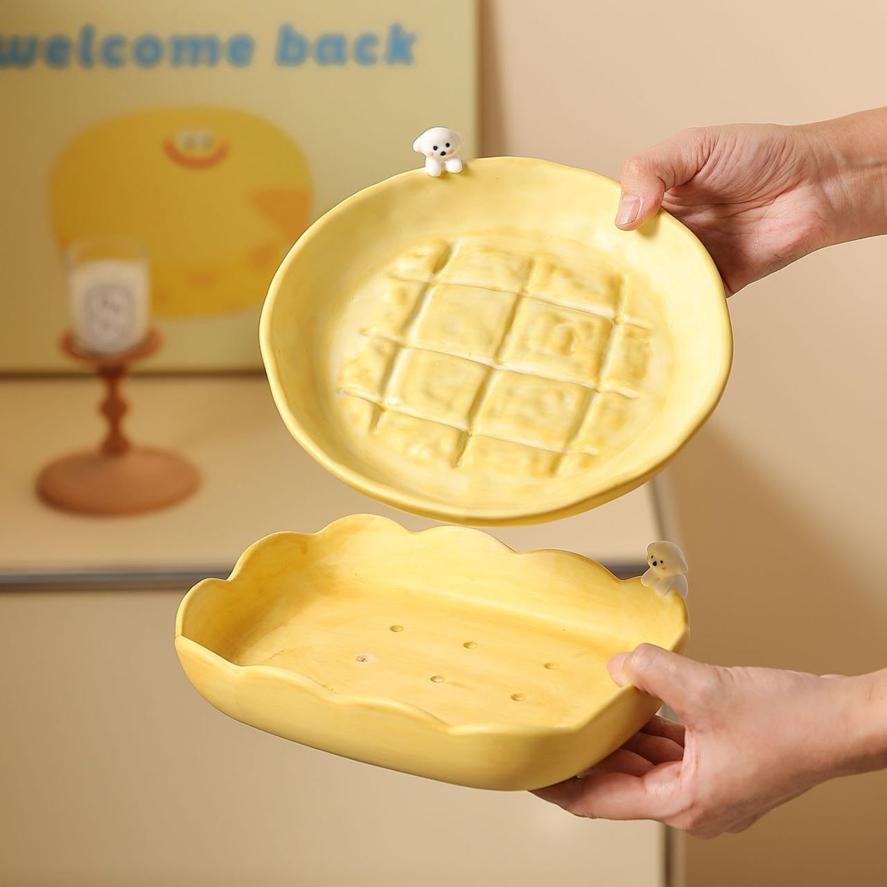 Yellow ceramic dish with waffle design held by a person, with a 'welcome back' sign in the background.