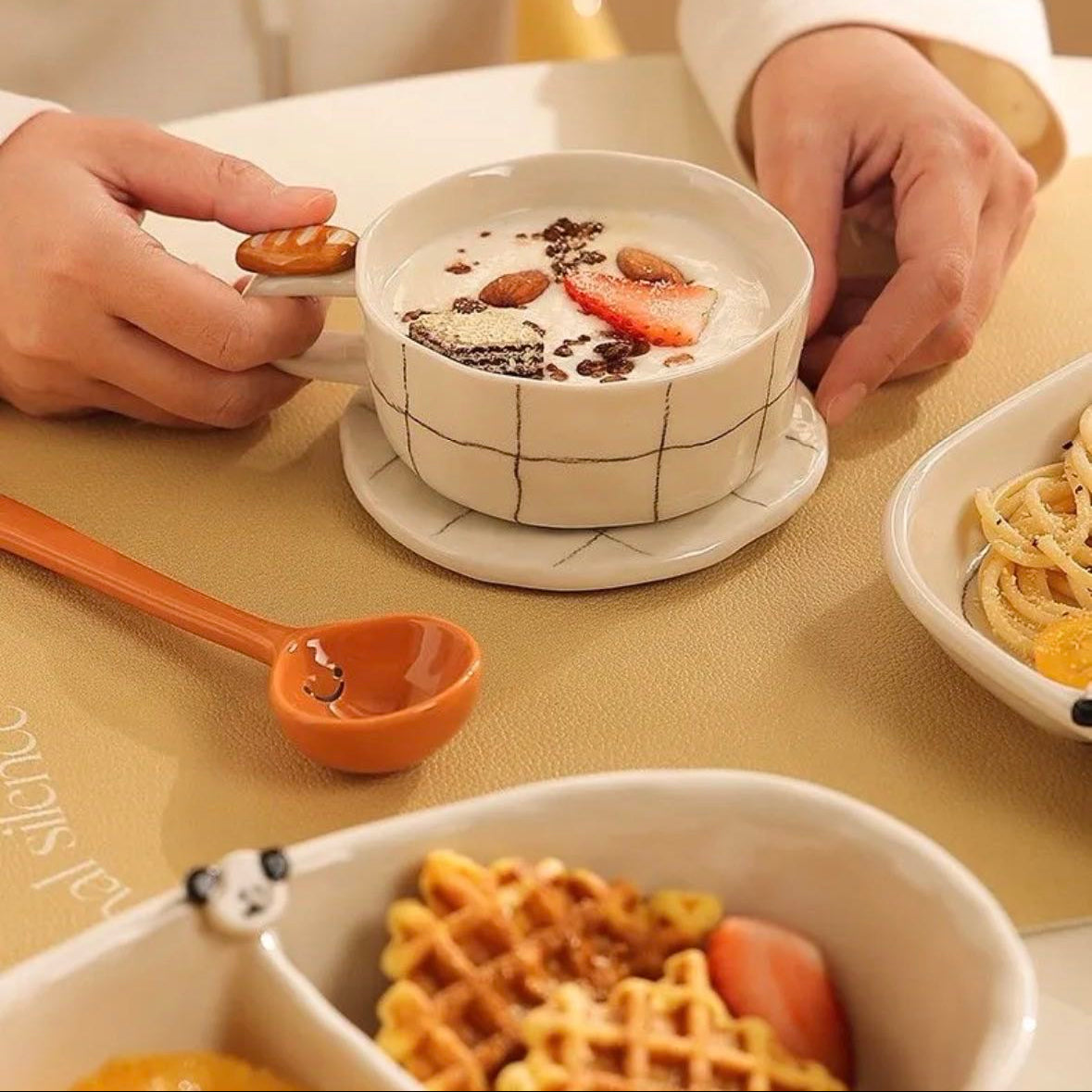Person holding a bowl of dessert with waffles and a spoon on a table.