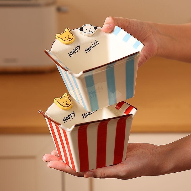 Two small ceramic pots with striped designs and 'Happy Health' text, held by a person.