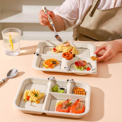 Children's divided plate with cartoon designs filled with food, held by a person.