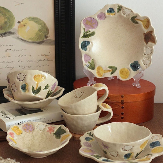 Set of ceramic tea cups and saucers with floral designs on a wooden surface.