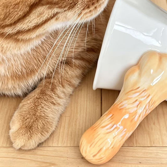 Cat paw tilt mug — orange tabby cat with orange ceramic mug, optical illusion tilt design, MeowCeramics